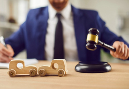 Lawyer advising clients on car accident claims, with a gavel and wooden car models
