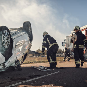 Firefighters responding to a flipped fatal vehicle accident on a road with rescue equipment nearby - Russo Law