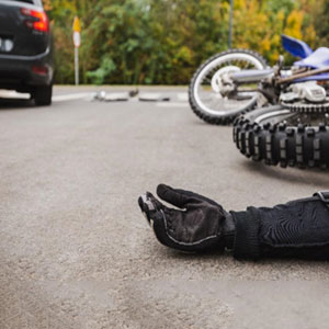 A person lying on the ground next to a motorcycle - Russo Law