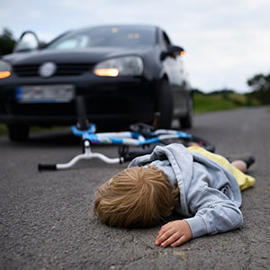 Injured Child: Child lying in the road next to a bicycle and car, suggesting injury by a Teen Driver in Florida.