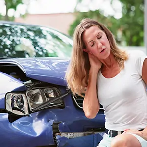 Woman with neck pain in front of a damaged car, related to hidden injuries after a car accident in Polk County, Florida.